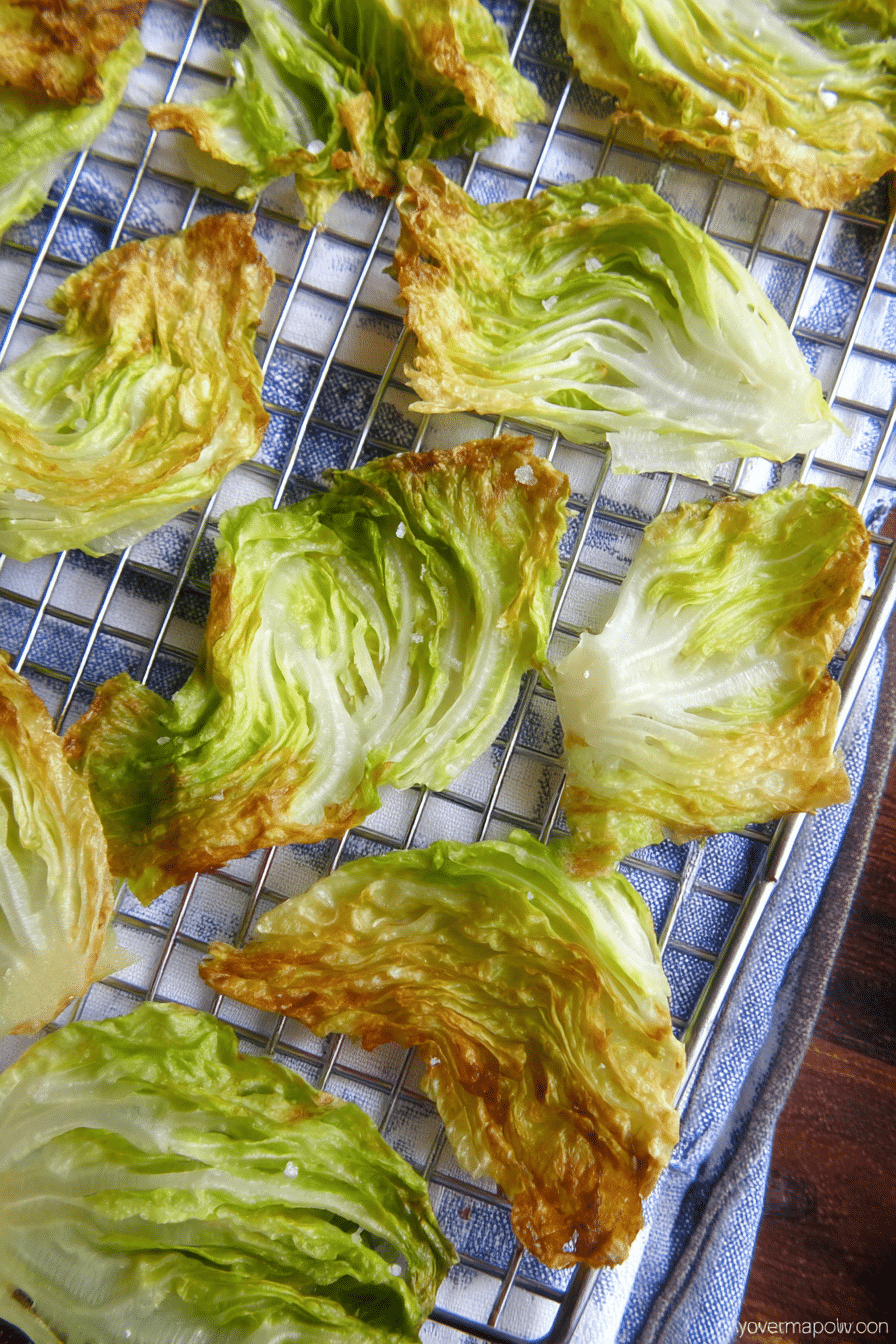 Close-up of golden-brown crispy baked cabbage chips in a bowl, garnished with sea salt.