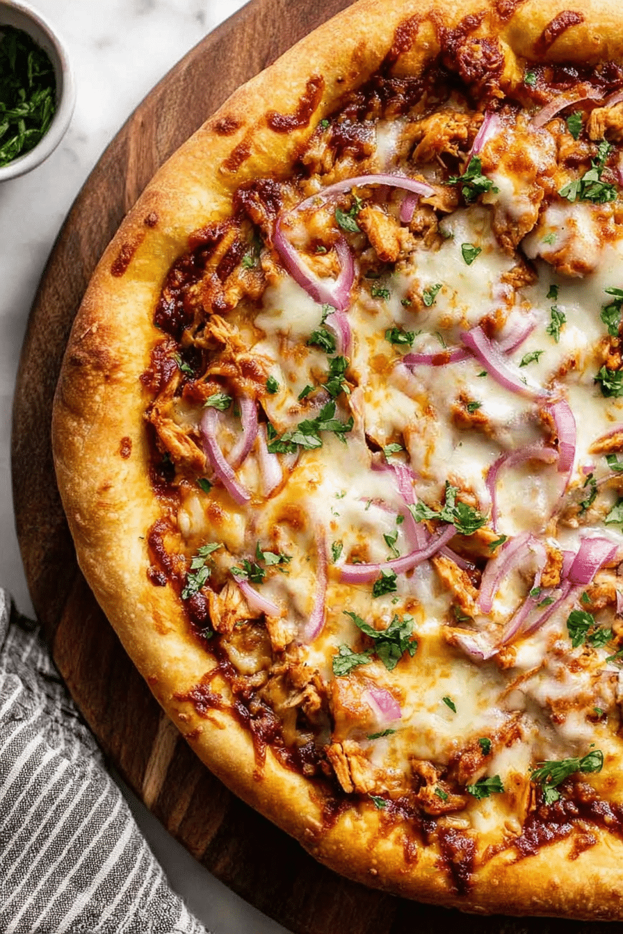 Close-up of a delicious homemade BBQ chicken pizza topped with mozzarella, smoked gouda, red onions, and cilantro.