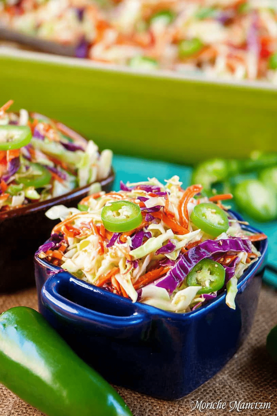 Cajun Honey Jalapeño Slaw served in a bowl with jalapeño slices and honey drizzle on a wooden table.