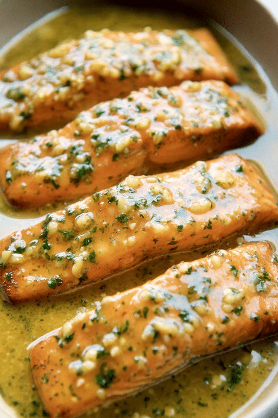 Plated garlic butter salmon with lemon wedges and parsley on a rustic wooden table