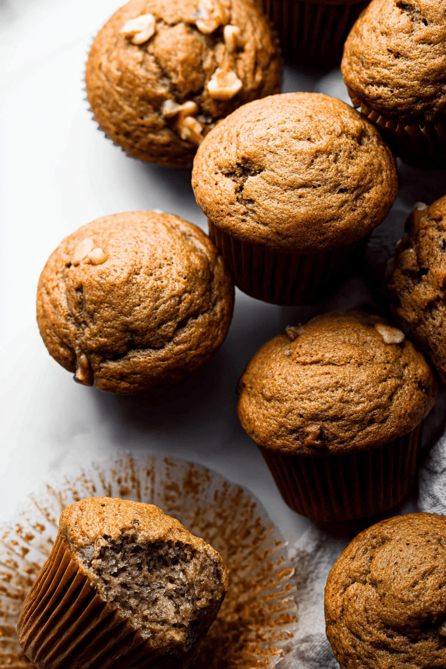Freshly baked banana muffins on a tray, garnished with walnuts and banana slices, highlighting their soft texture and golden brown color.