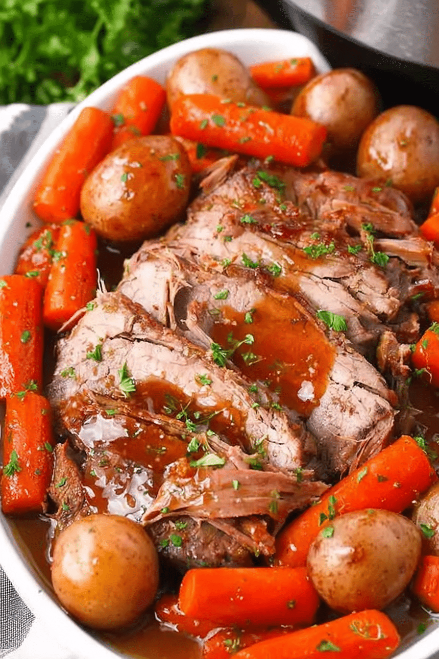 Delicious Slow Cooker Yankee Pot Roast served with carrots, potatoes, and gravy on a rustic wooden table.
