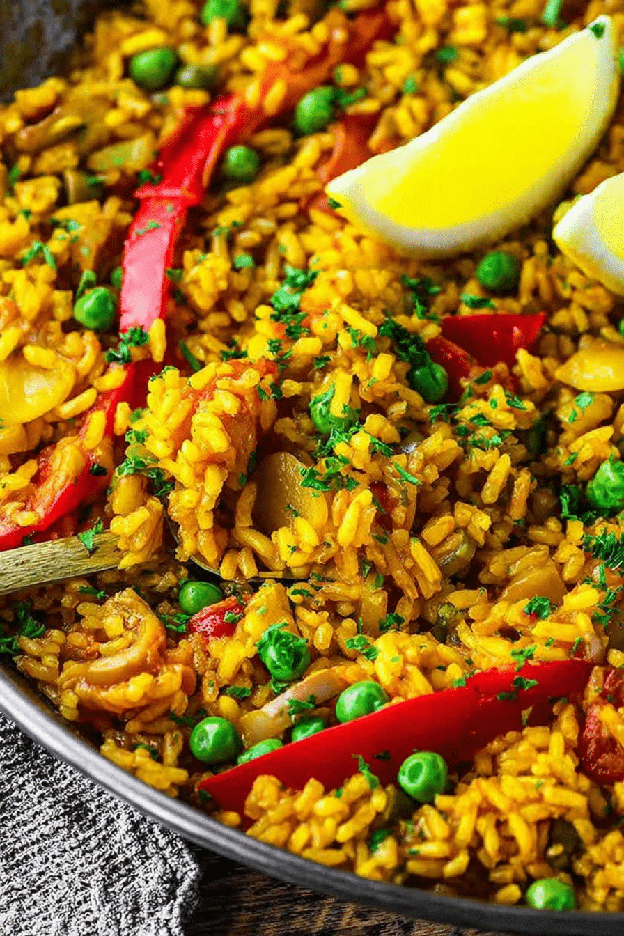 Delicious vegan paella served with colorful vegetables and lemon wedges.