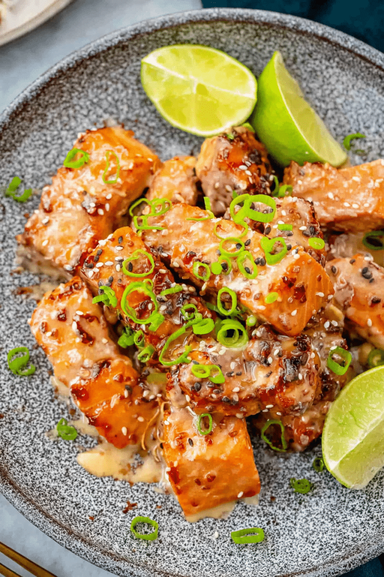 Close-up of crispy Bang Bang Salmon pieces topped with tangy sauce and lime, garnished with fresh herbs.