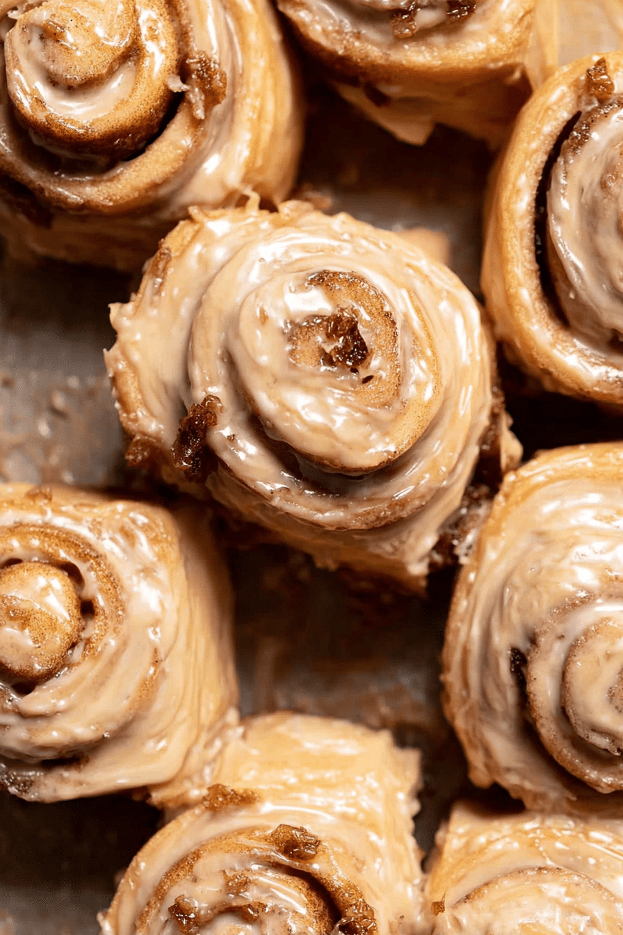 Freshly baked coffee rolls with cream cheese frosting and coffee bean garnish on a wooden table.