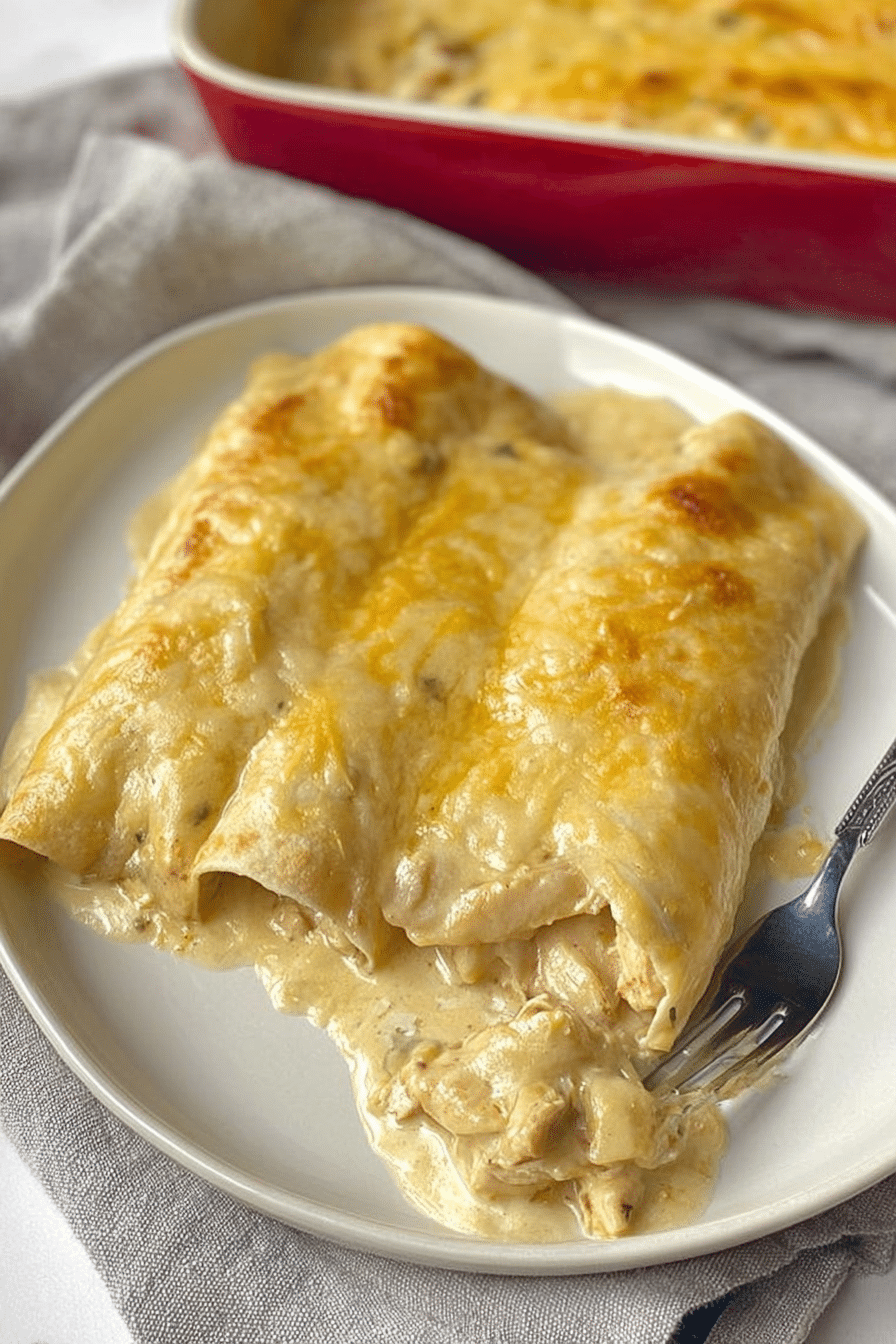 Close-up of creamy white chicken enchiladas topped with melted cheese and garnishes on a decorative plate.