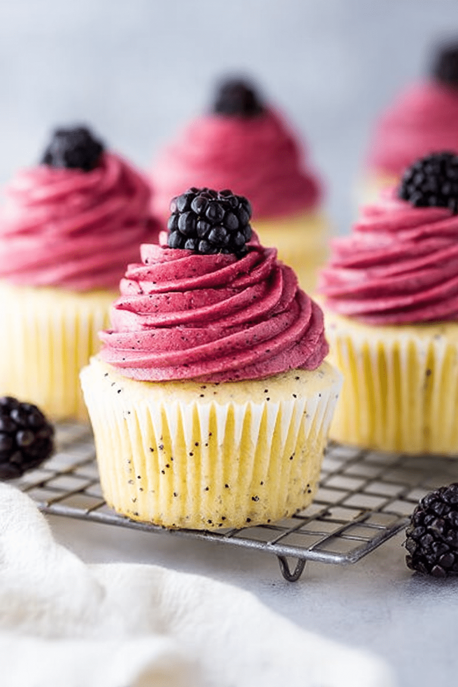 Lemon poppy seed cupcake with blackberry frosting and fresh blackberries on top.