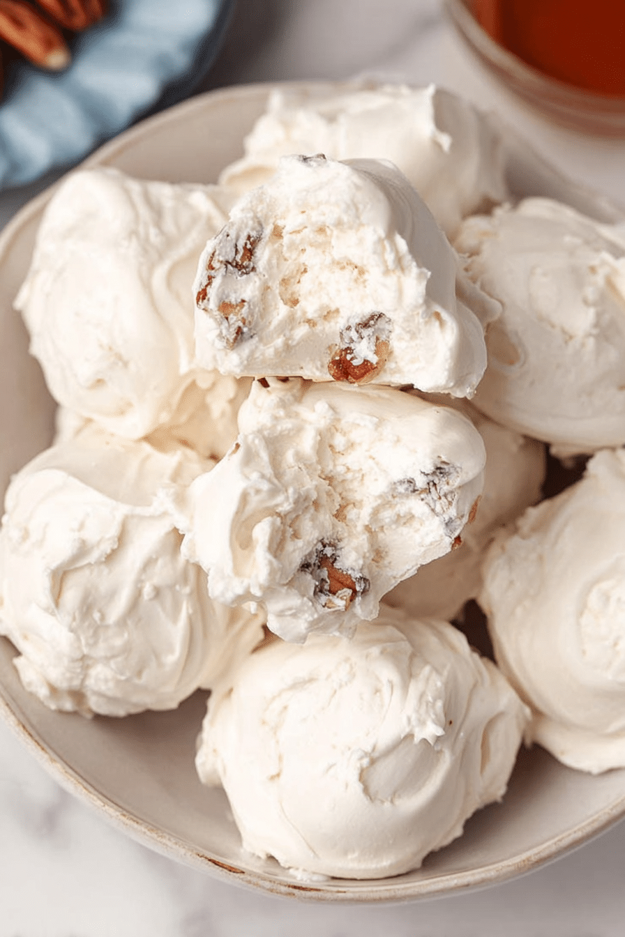 Close-up of old-fashioned divinity candy pieces on a vintage plate, highlighting their airy texture and pecan topping.