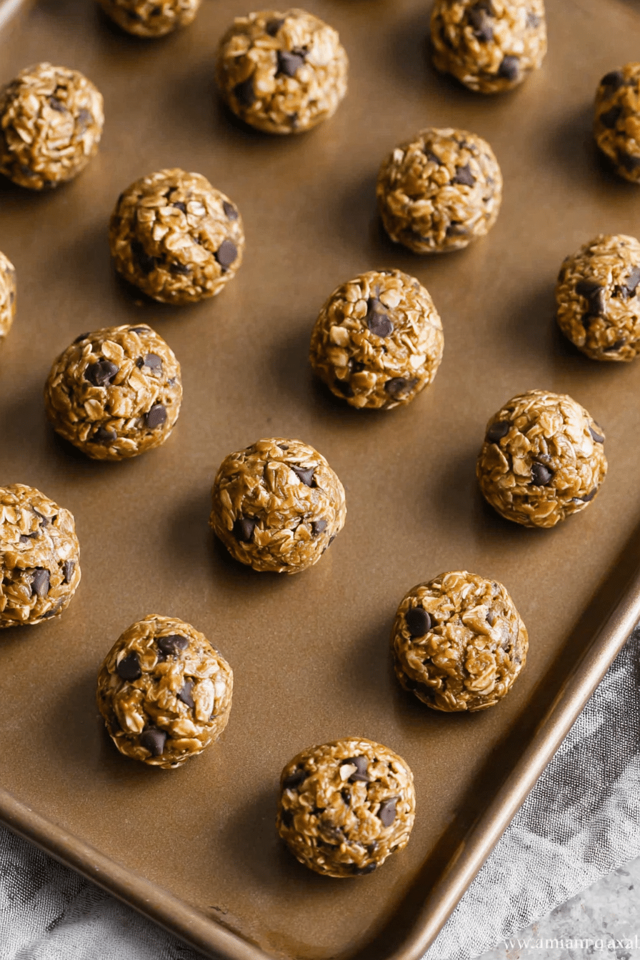Delicious peanut butter oat balls on a wooden board, surrounded by rolled oats and chocolate chips, showcasing a healthy snack option.