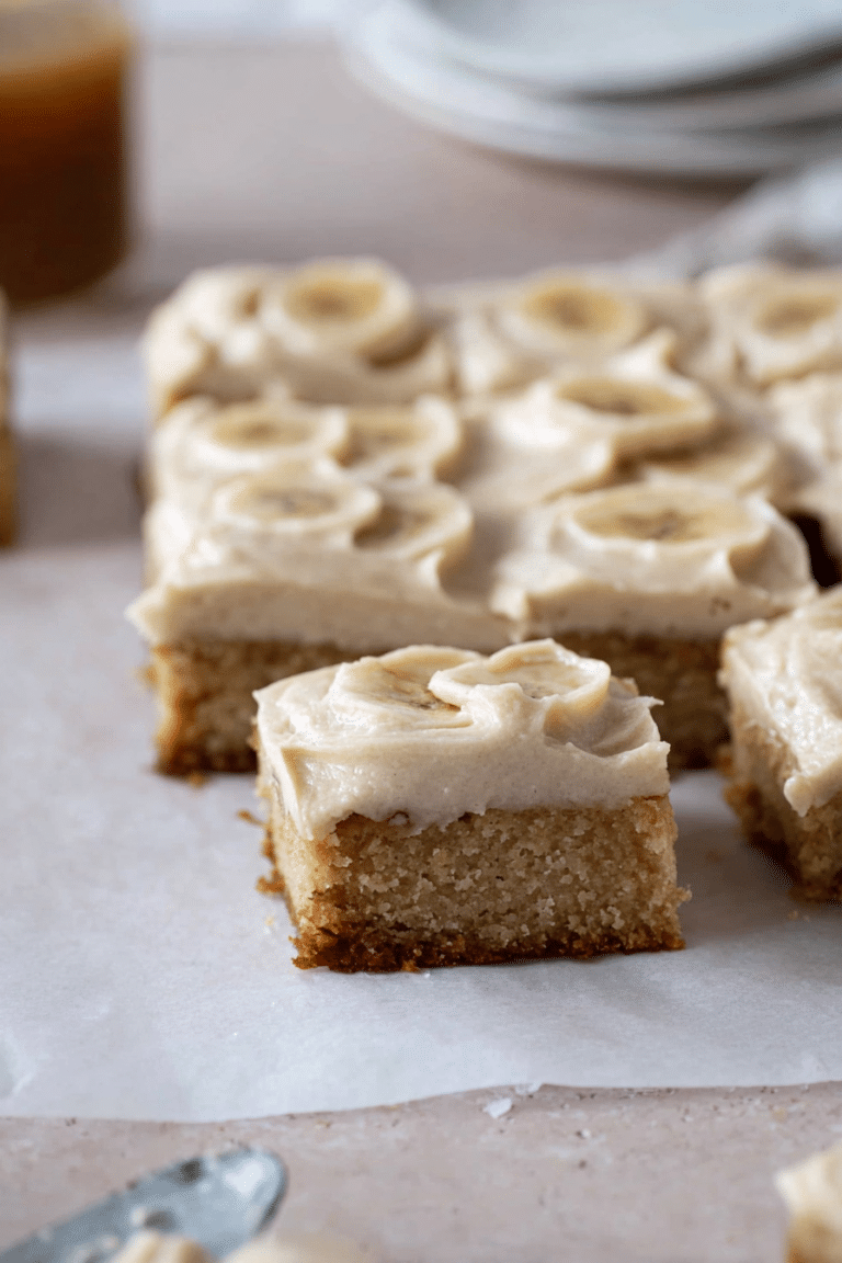 Delicious banana bars with brown butter icing and banana slices on a rustic wooden plate.