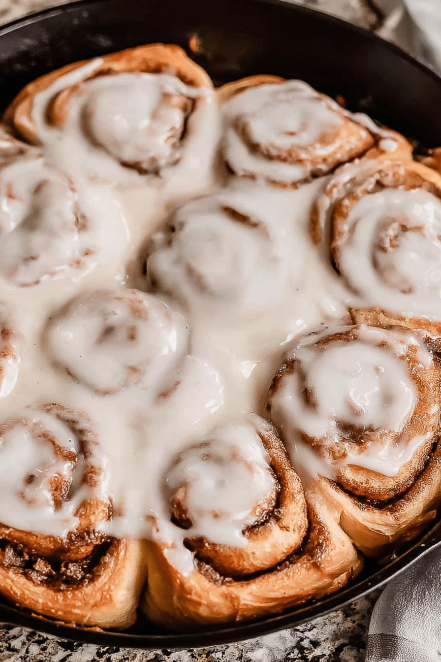 Delicious freshly baked sourdough cinnamon rolls with creamy glaze on a wooden table.