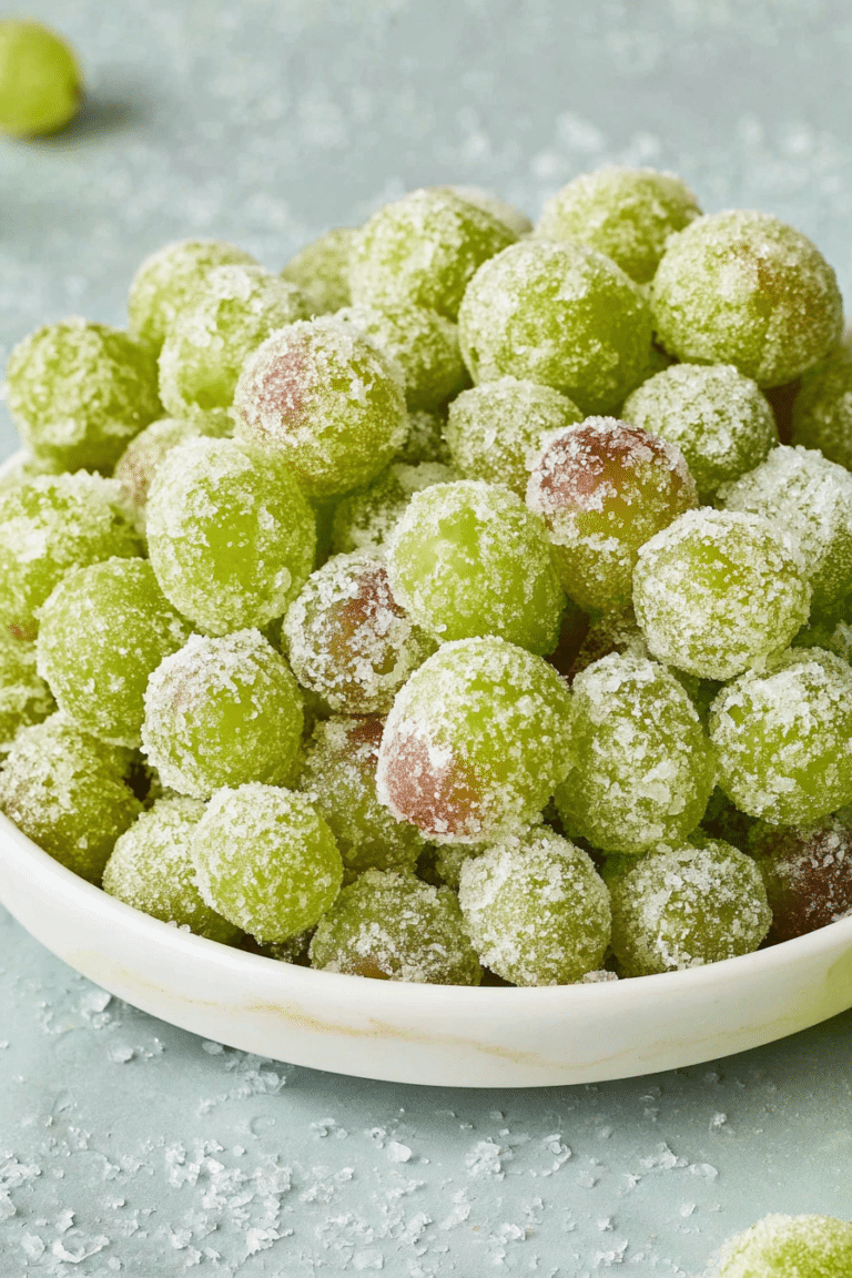 Close-up of frozen candied grapes on a decorative plate, highlighting their vibrant green color and sweet coating.