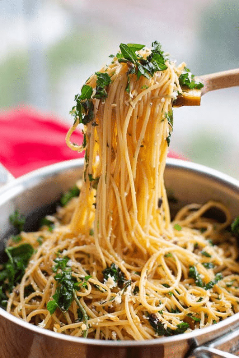Close-up of garlic butter spaghetti with herbs topped with fresh basil and grated Parmesan cheese.