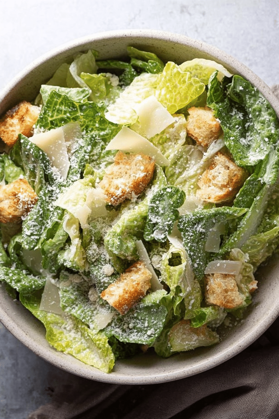 Homemade Caesar salad in a bowl with croutons, Parmesan cheese, and lemon slices.