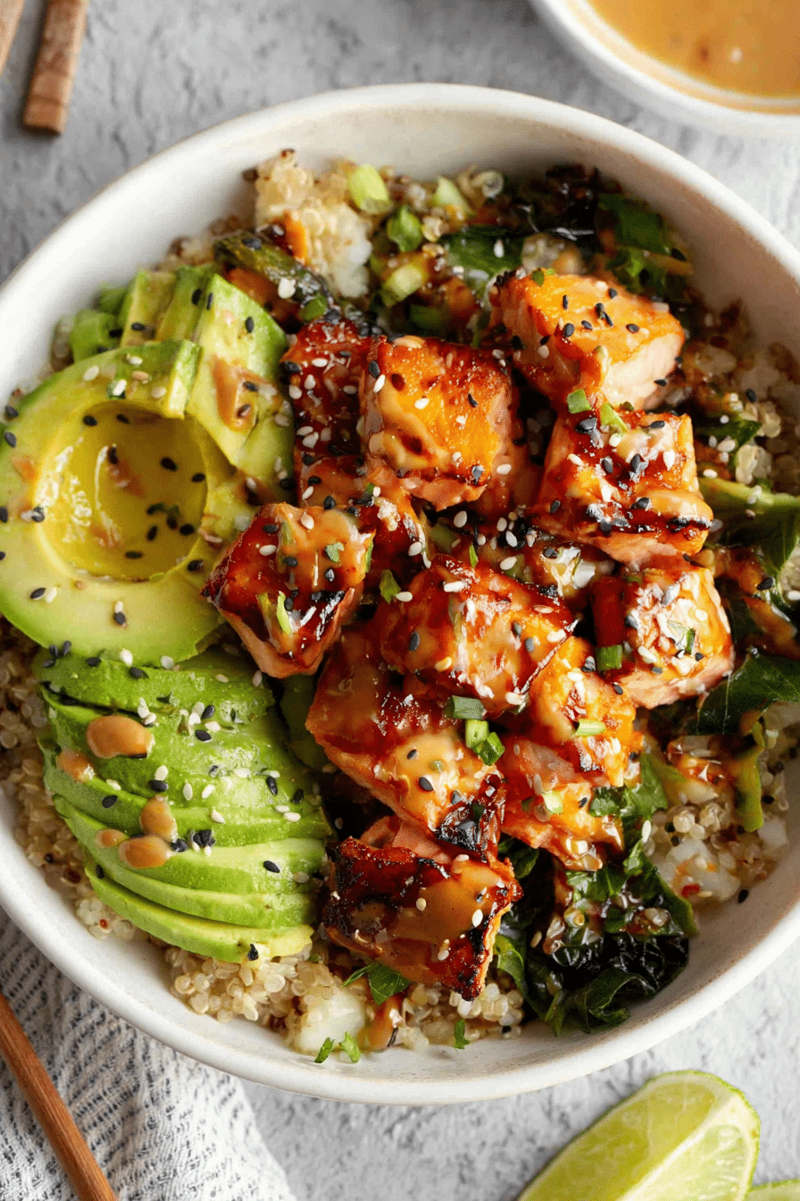 Honey glazed salmon rice bowl topped with avocado, cucumber, and cilantro on a white background.