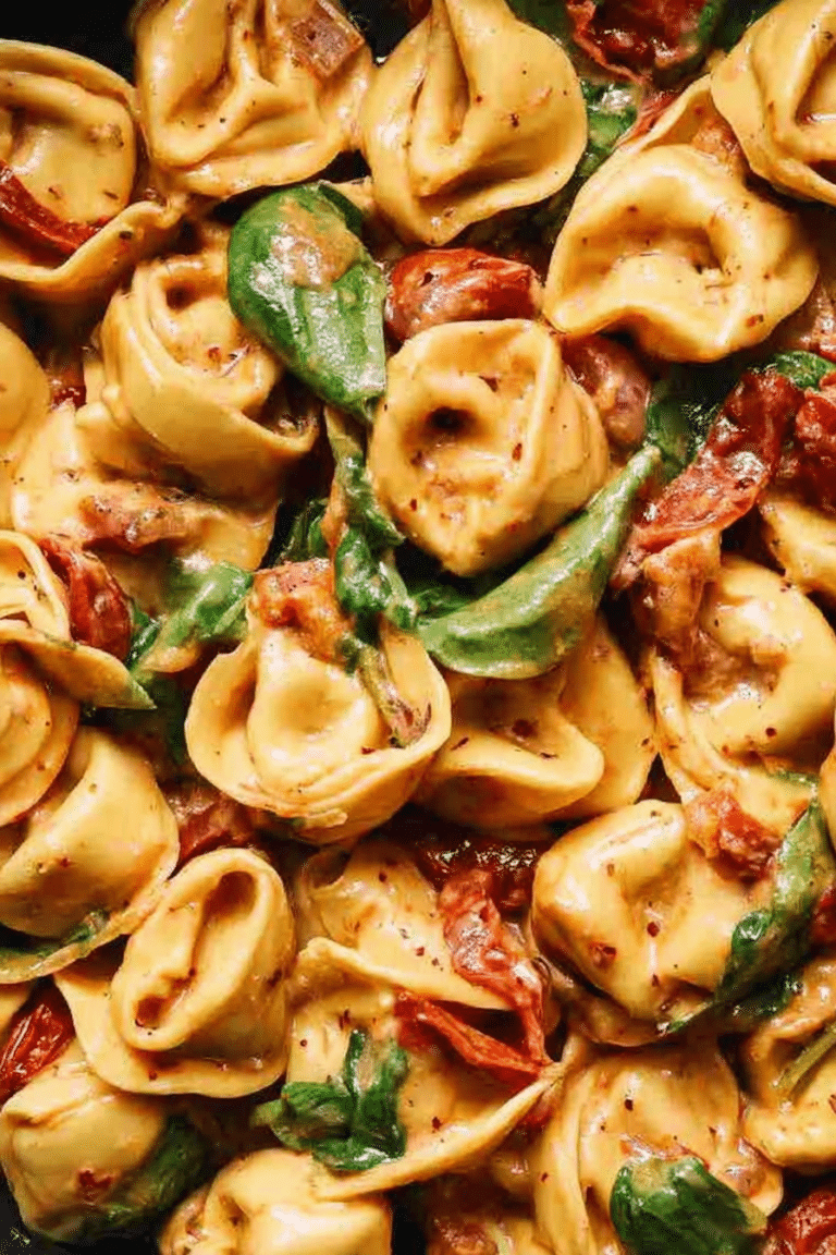 A bowl of creamy Marry Me Tortellini with fresh spinach and Parmigiano cheese on a rustic wooden table.