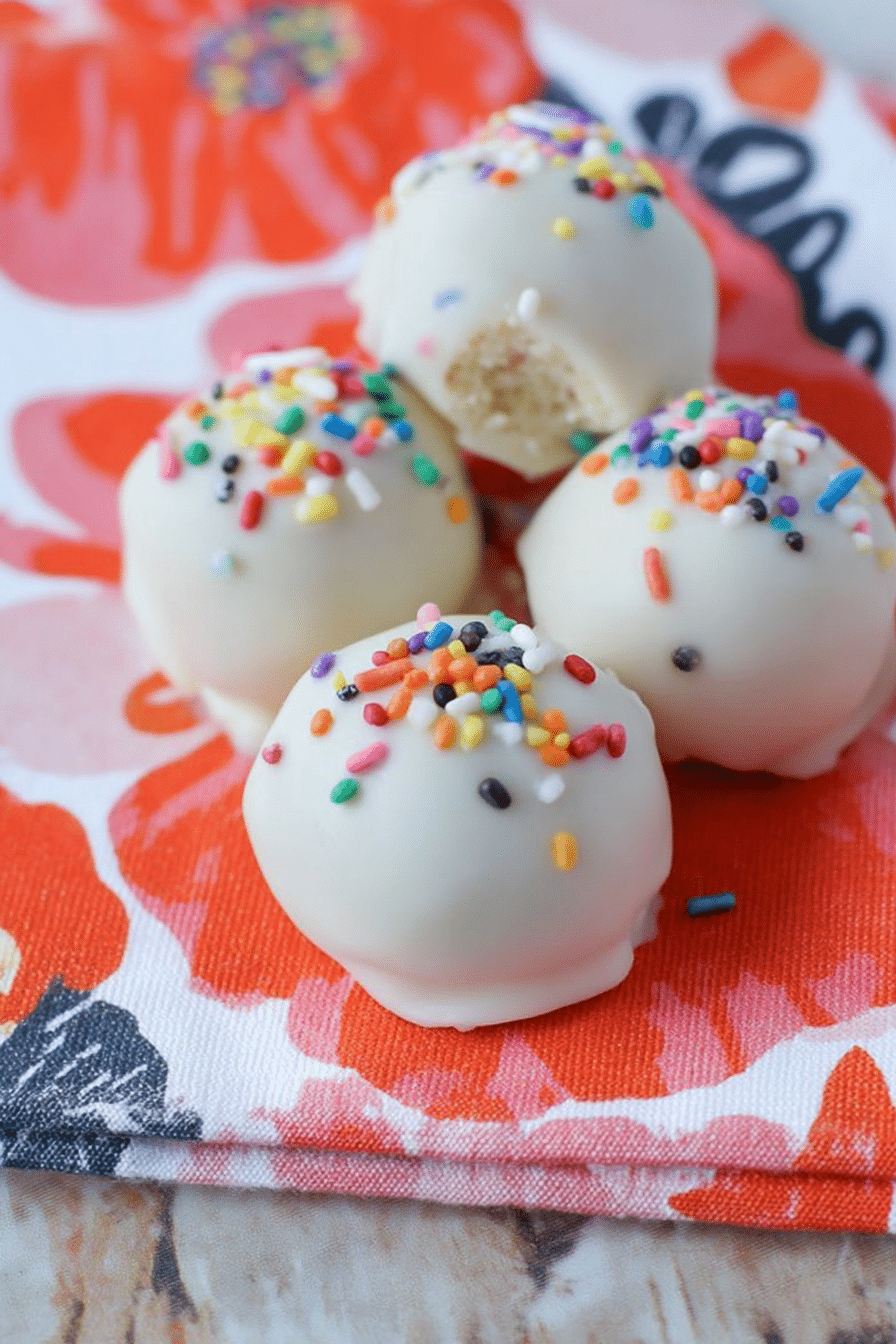 Delicious no-bake cake batter truffles topped with colorful sprinkles on a decorative plate.