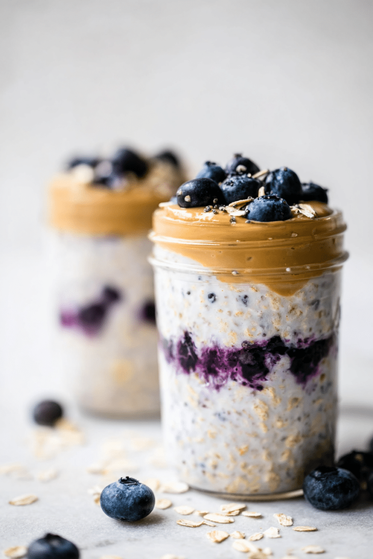 Close-up of a mason jar filled with peanut butter blueberry overnight oats topped with blueberries and peanut butter.