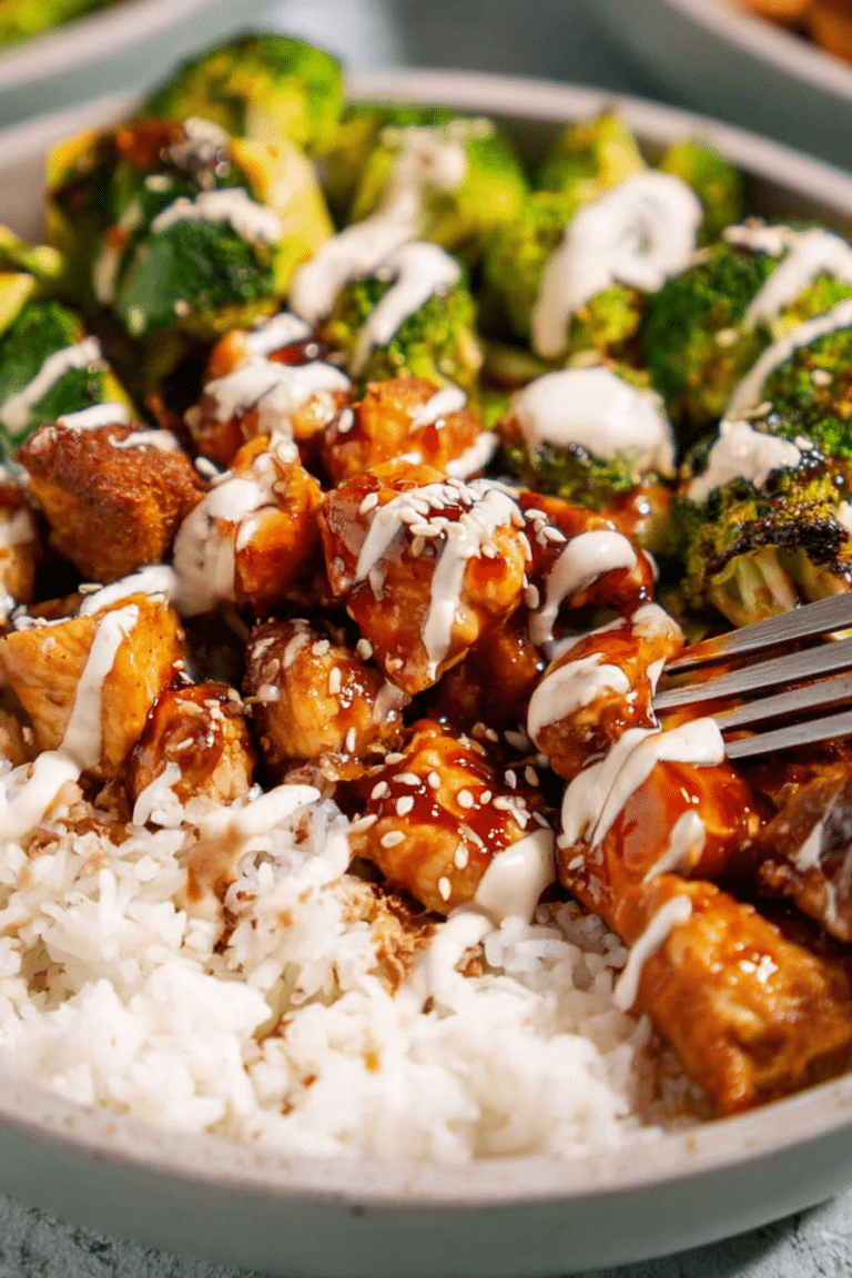 Delicious sticky chicken bowl garnished with green onions and sesame seeds, showcasing chicken, broccoli, and fluffy rice.