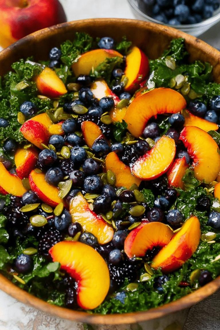 A colorful summer peach blueberry kale salad in a bowl with peaches, blueberries, kale, and pepitas.