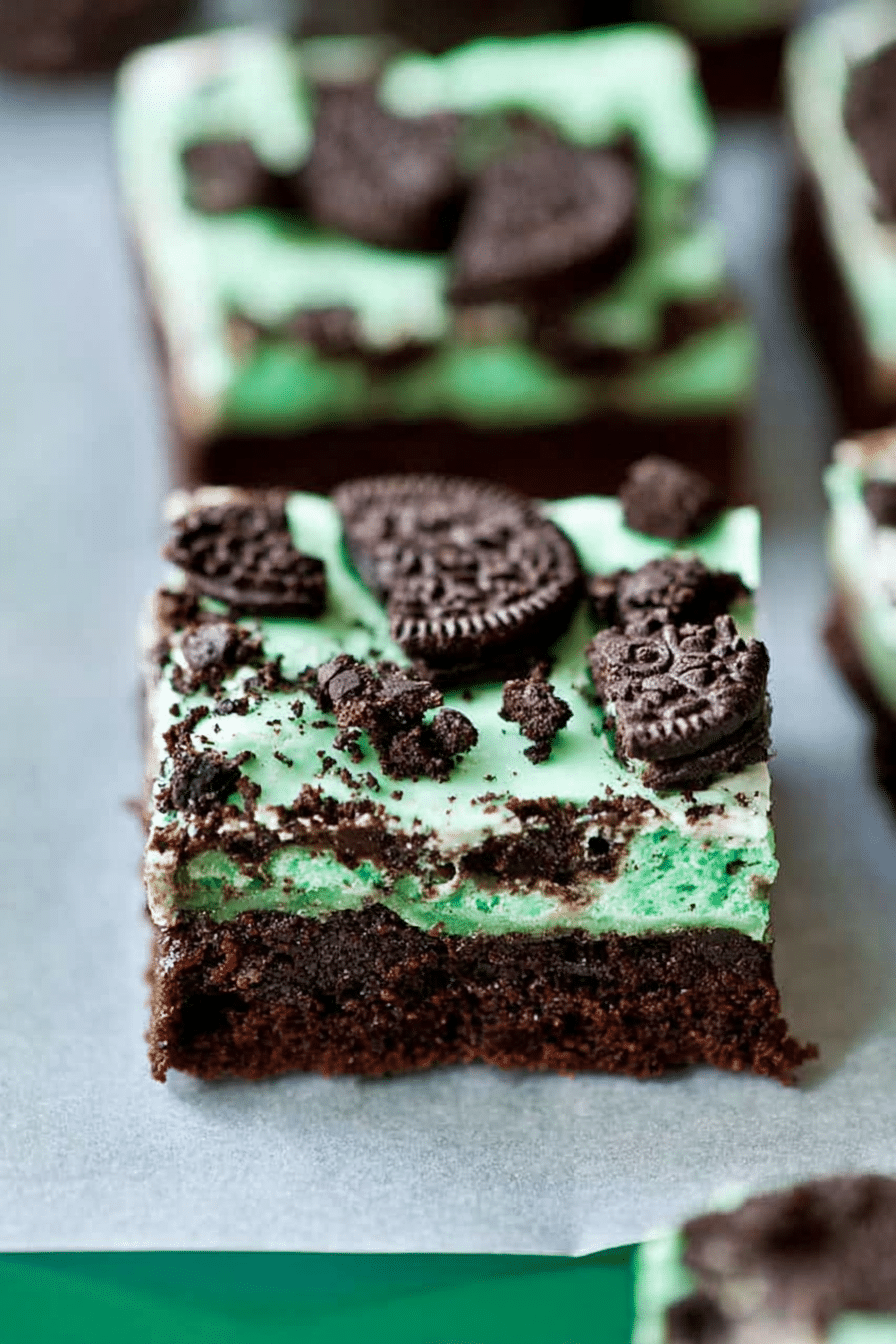 Close-up of triple layer fudgy mint Oreo brownies with visible layers of chocolate, mint frosting, and crushed Oreos.