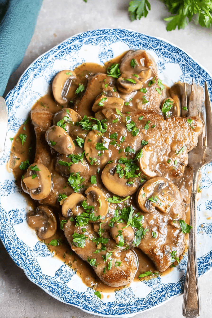 Veal Marsala served with mashed potatoes and green beans, garnished with parsley.