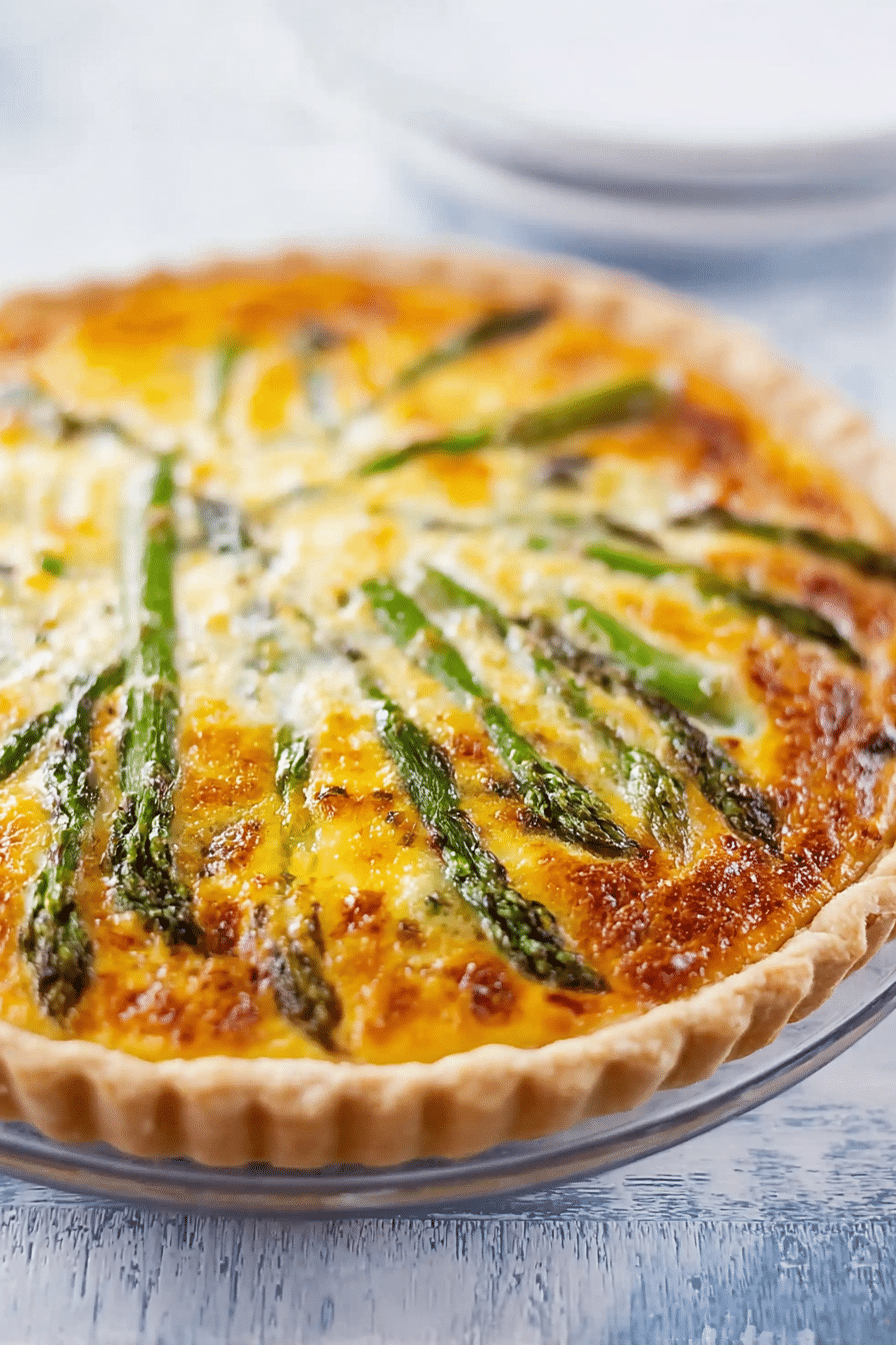 Delicious homemade asparagus quiche with feta cheese on a wooden table.
