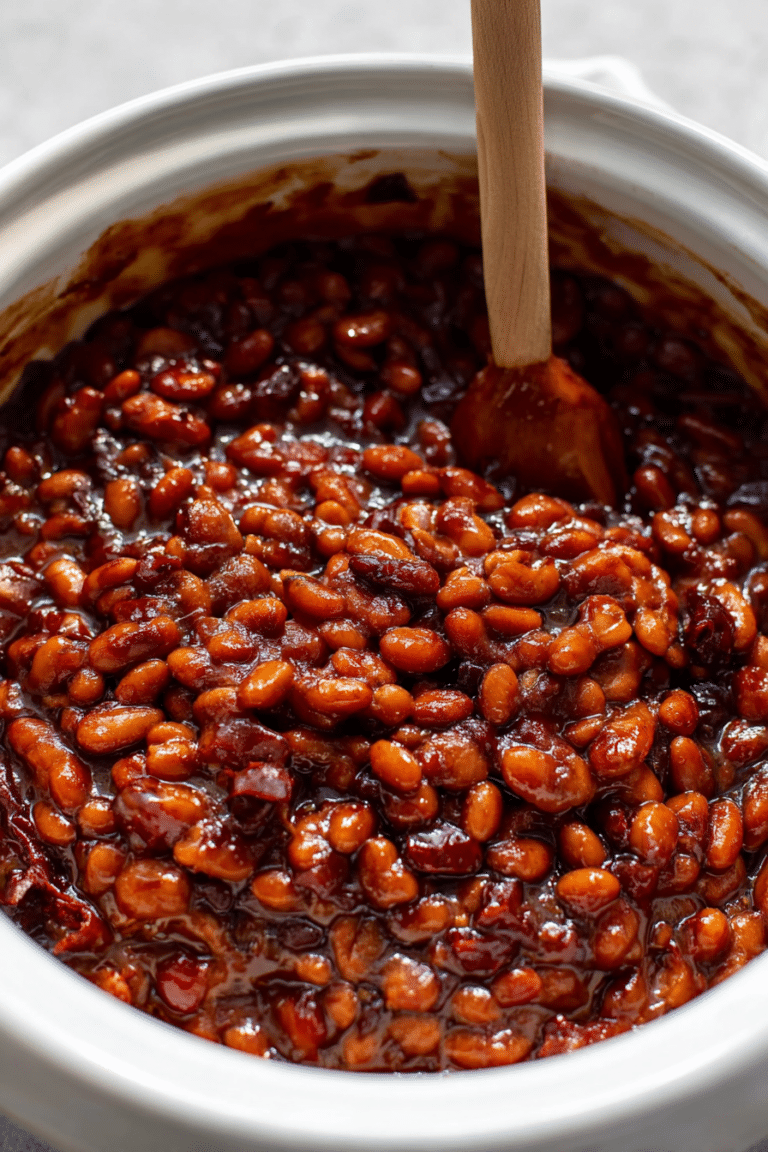 Delicious baked beans topped with crispy bacon, served in a rustic skillet.