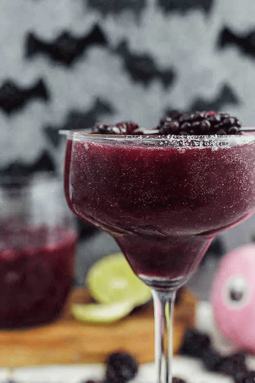 Black Magic Margarita in a glass, garnished with mint and blackberries, perfect for Halloween celebrations.
