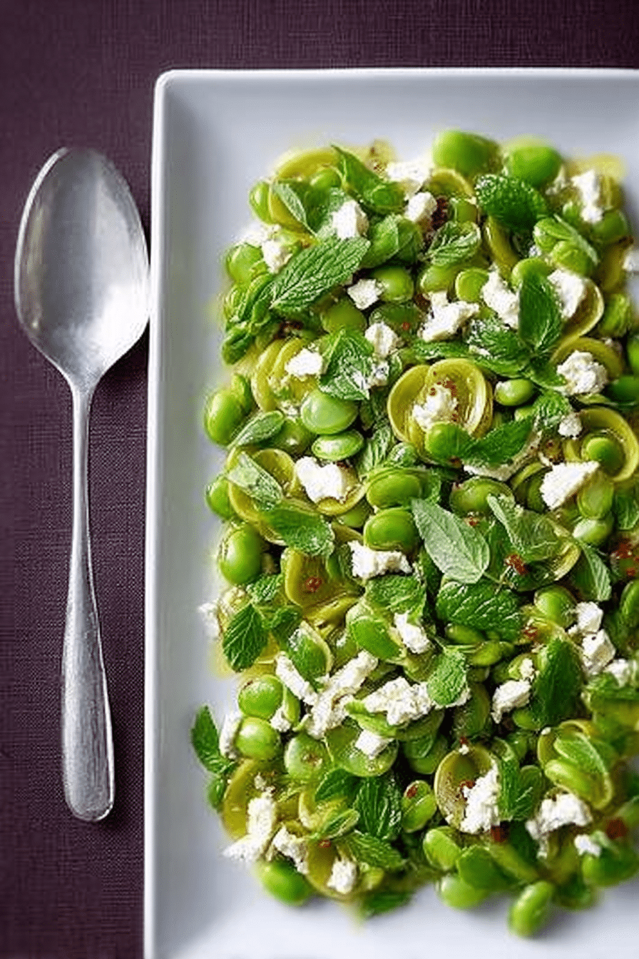Delicious broad bean salad with mint and feta drizzled with lemon oil, served in a rustic bowl.