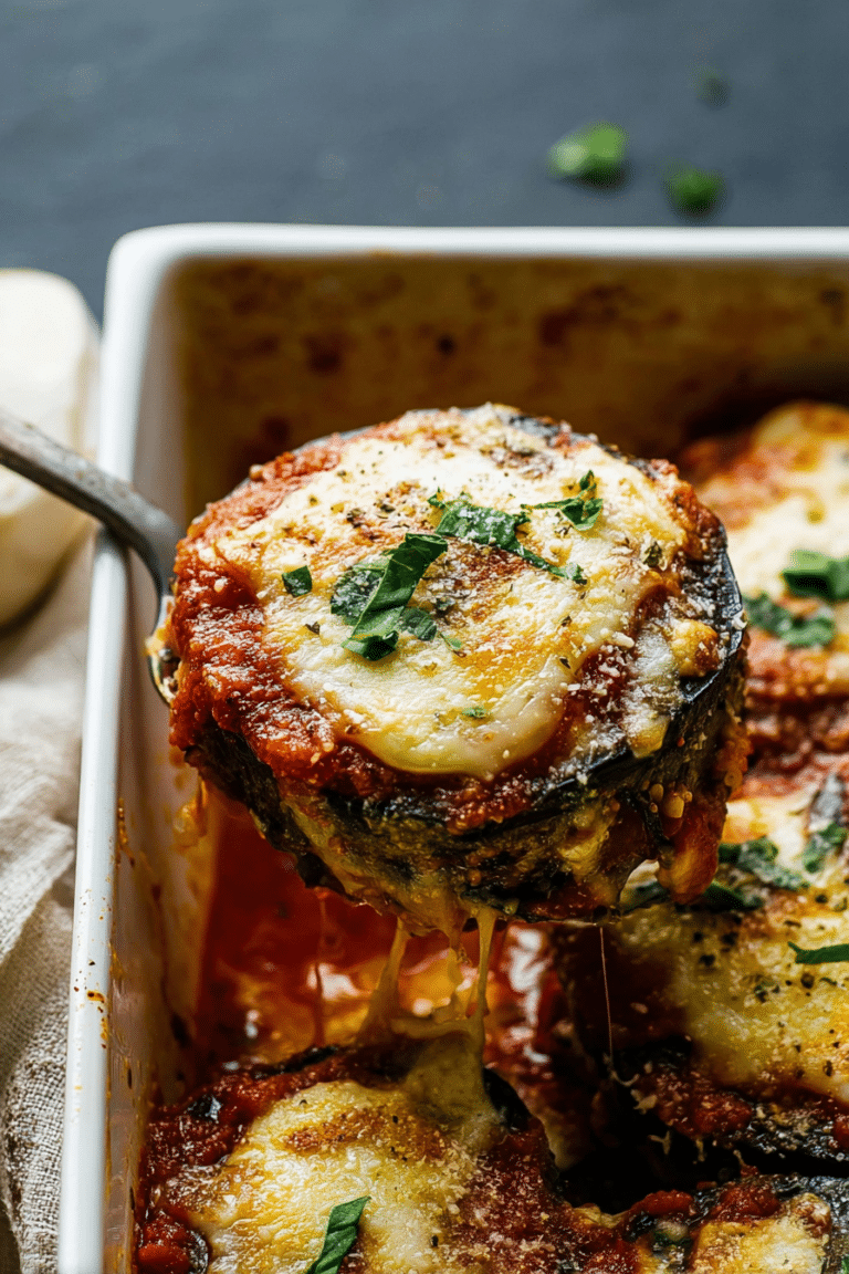 Classic eggplant parmesan with layers of breaded eggplant, melted cheese, and marinara sauce, garnished with fresh basil.