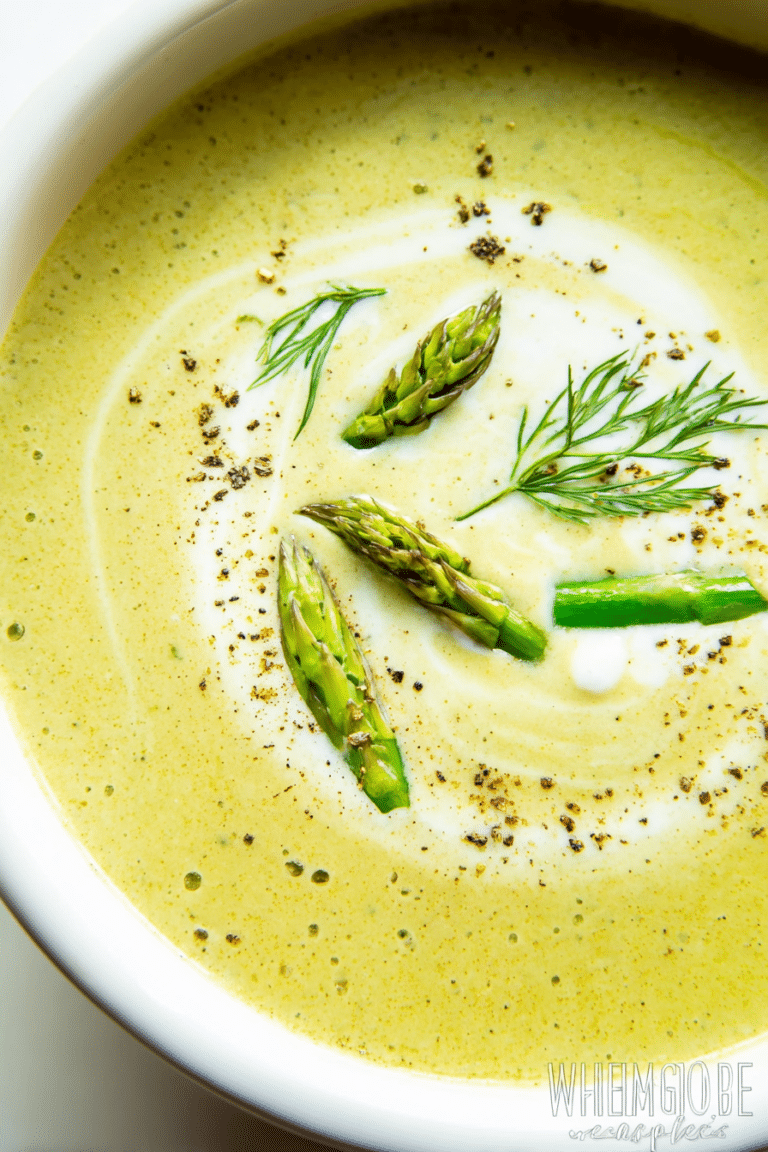 Cream of asparagus soup in a bowl with chives and cream garnish