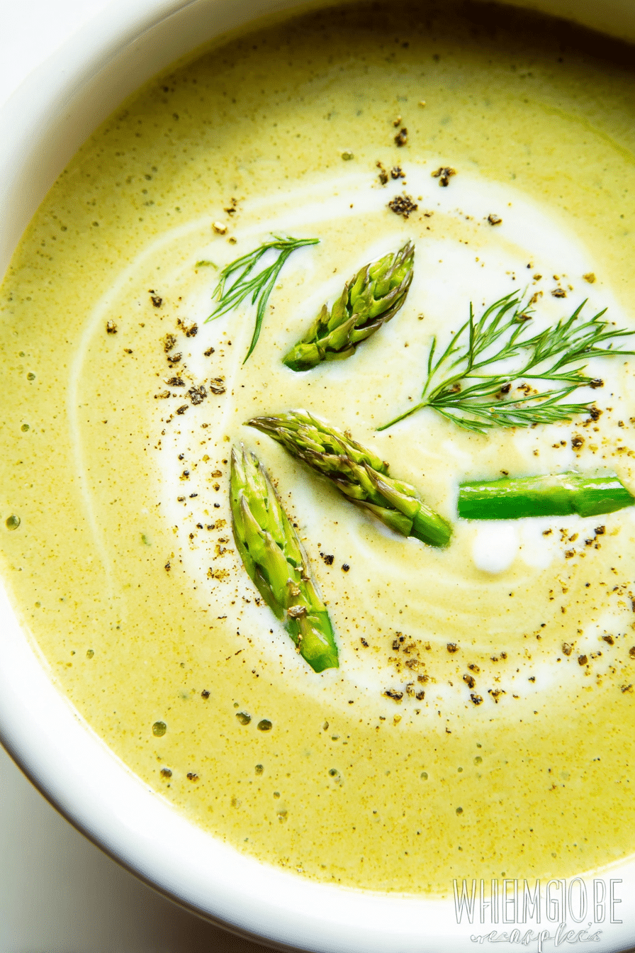 Cream of asparagus soup in a bowl with chives and cream garnish