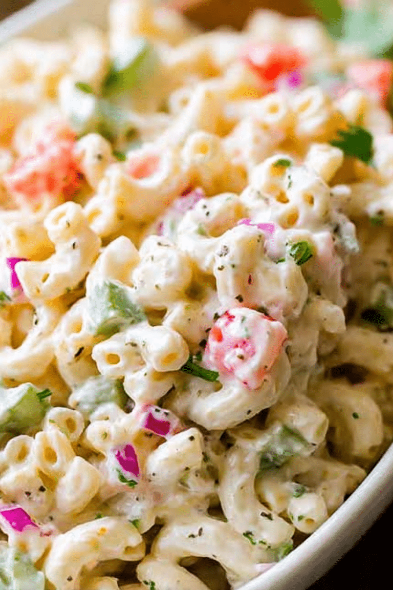 Vibrant creamy macaroni salad in a bowl with colorful vegetables and fresh herbs.