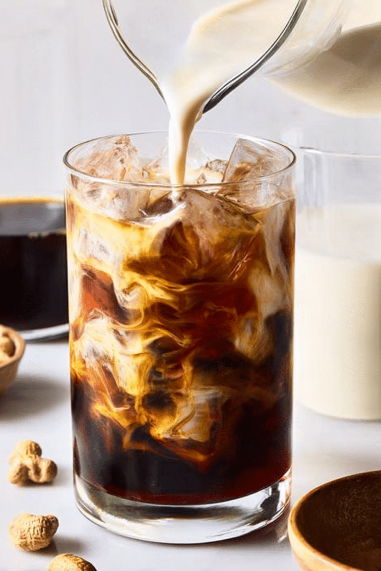 A refreshing glass of easy iced coffee with milk, ice cubes, and coffee beans in the background.