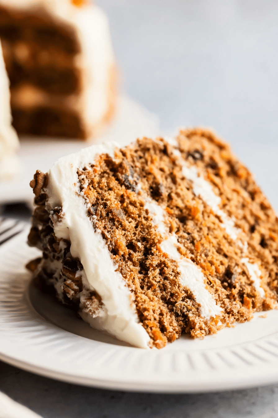 Slice of healthy carrot cake topped with shredded coconut and pecans, showcasing the moist texture and layers of the cake.