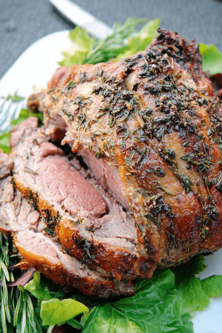 Herb roast leg of lamb garnished with fresh herbs on a rustic table