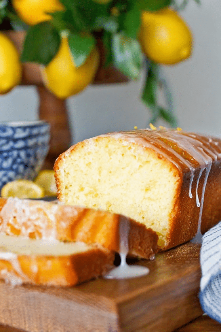 Slice of lemon pound cake with lemon glaze and garnishes on a plate