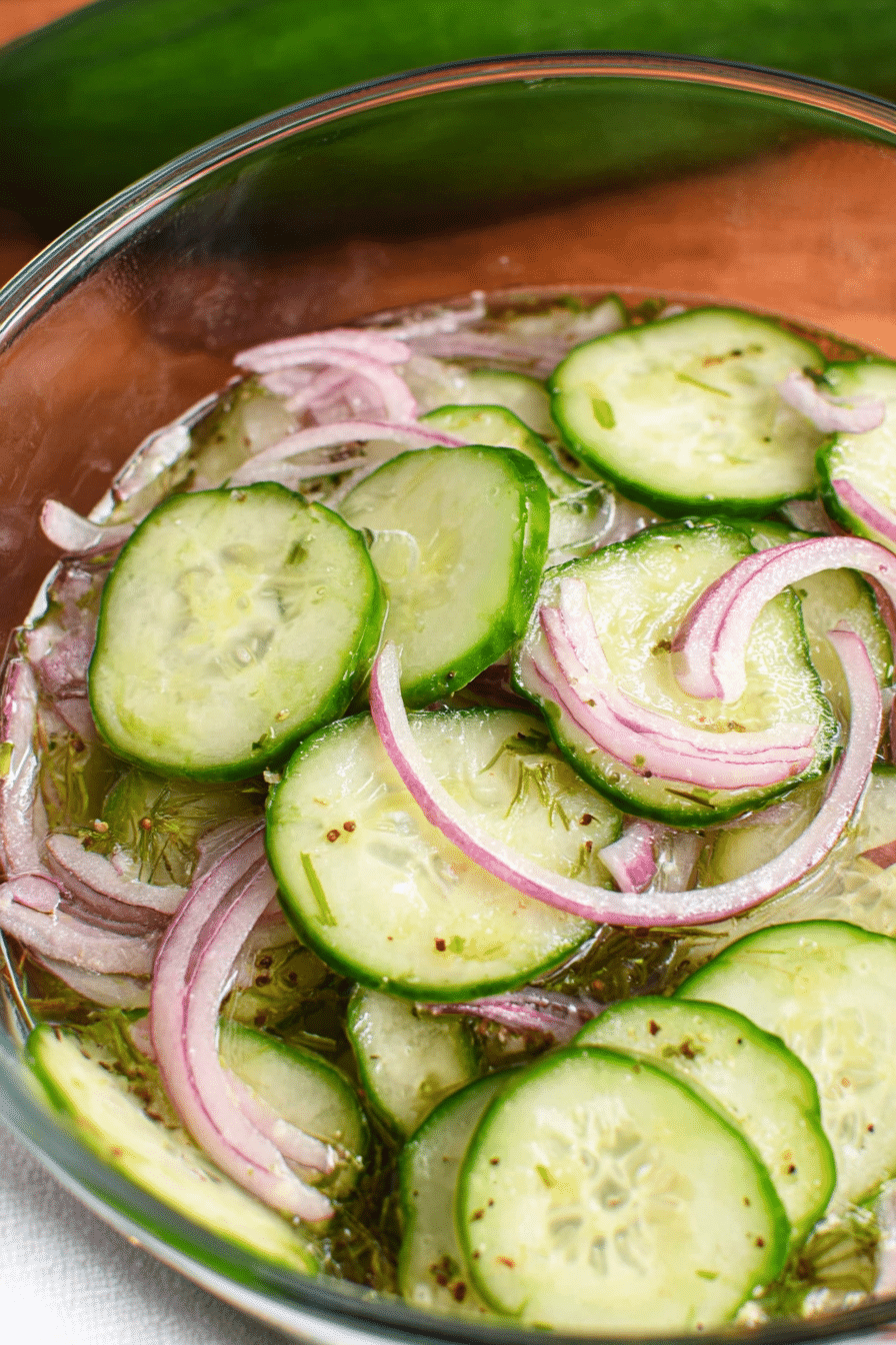 Old fashioned cucumber salad with cucumbers and red onions in vinegar dressing garnished with dill.