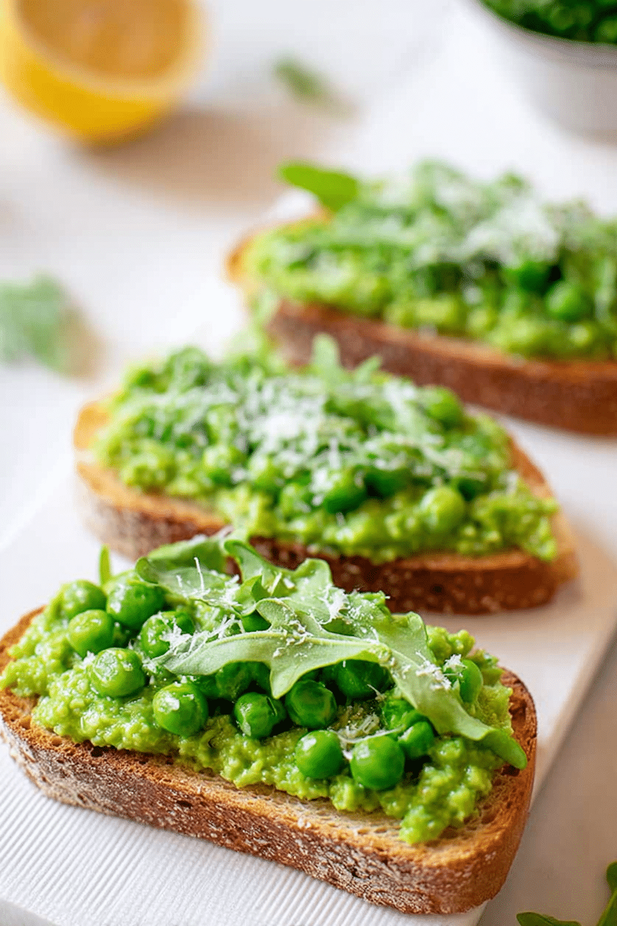 Delicious pea bruschetta with lemon zest and pea shoots on a rustic wooden table.