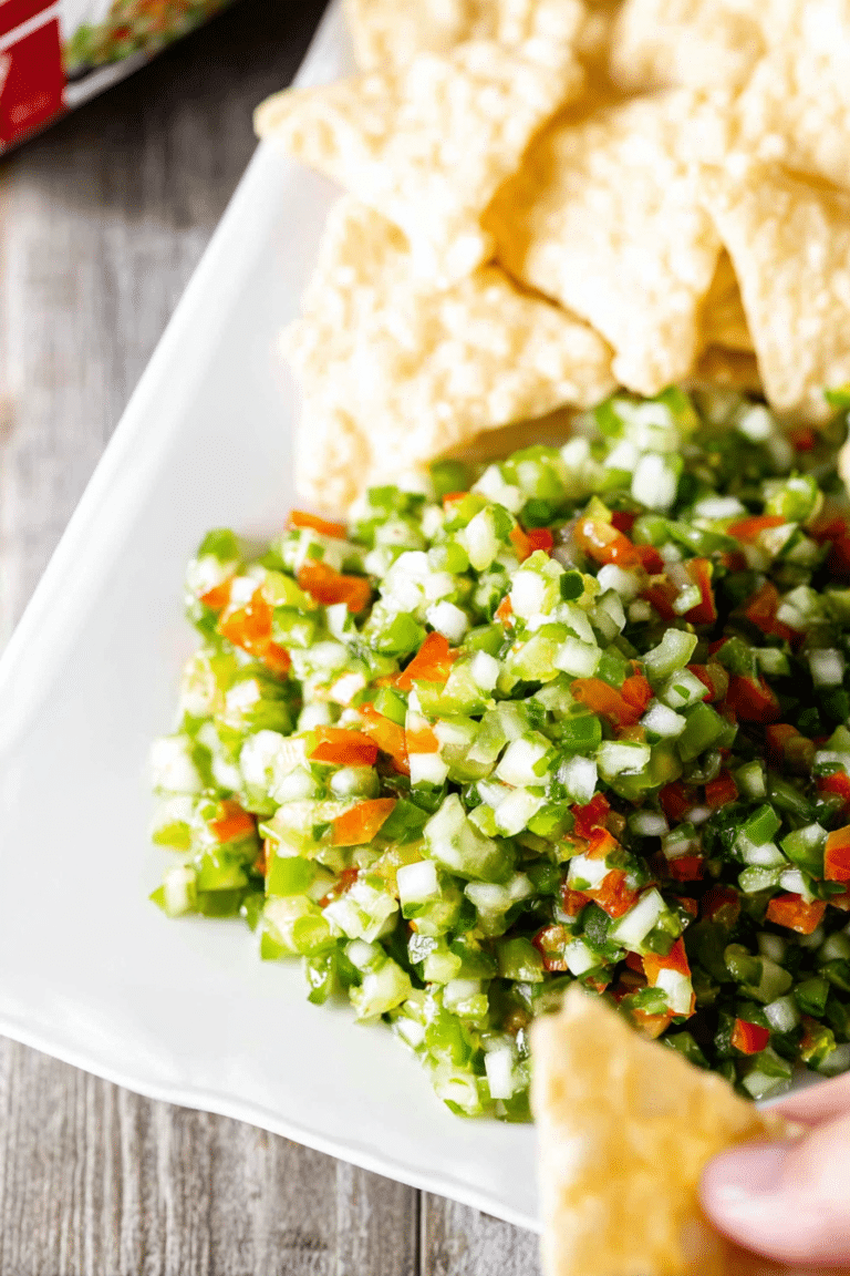 A vibrant bowl of pickle de gallo salsa with tortilla chips, fresh herbs, and colorful vegetables.