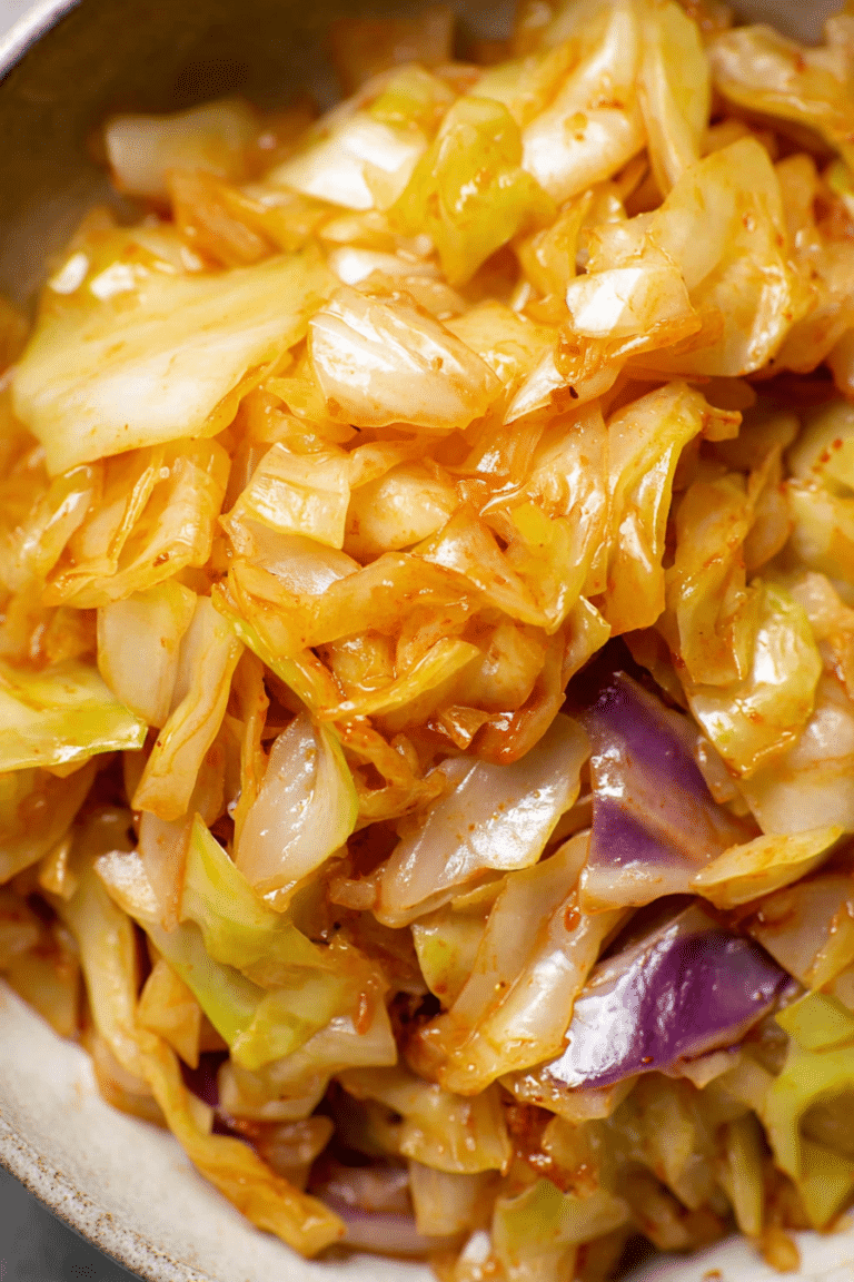 Close-up of sautéed cabbage with golden brown edges and garnished with herbs.
