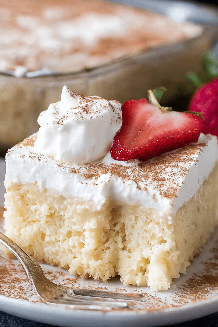 Sliced tres leches cake with whipped cream and cinnamon sprinkled on top.