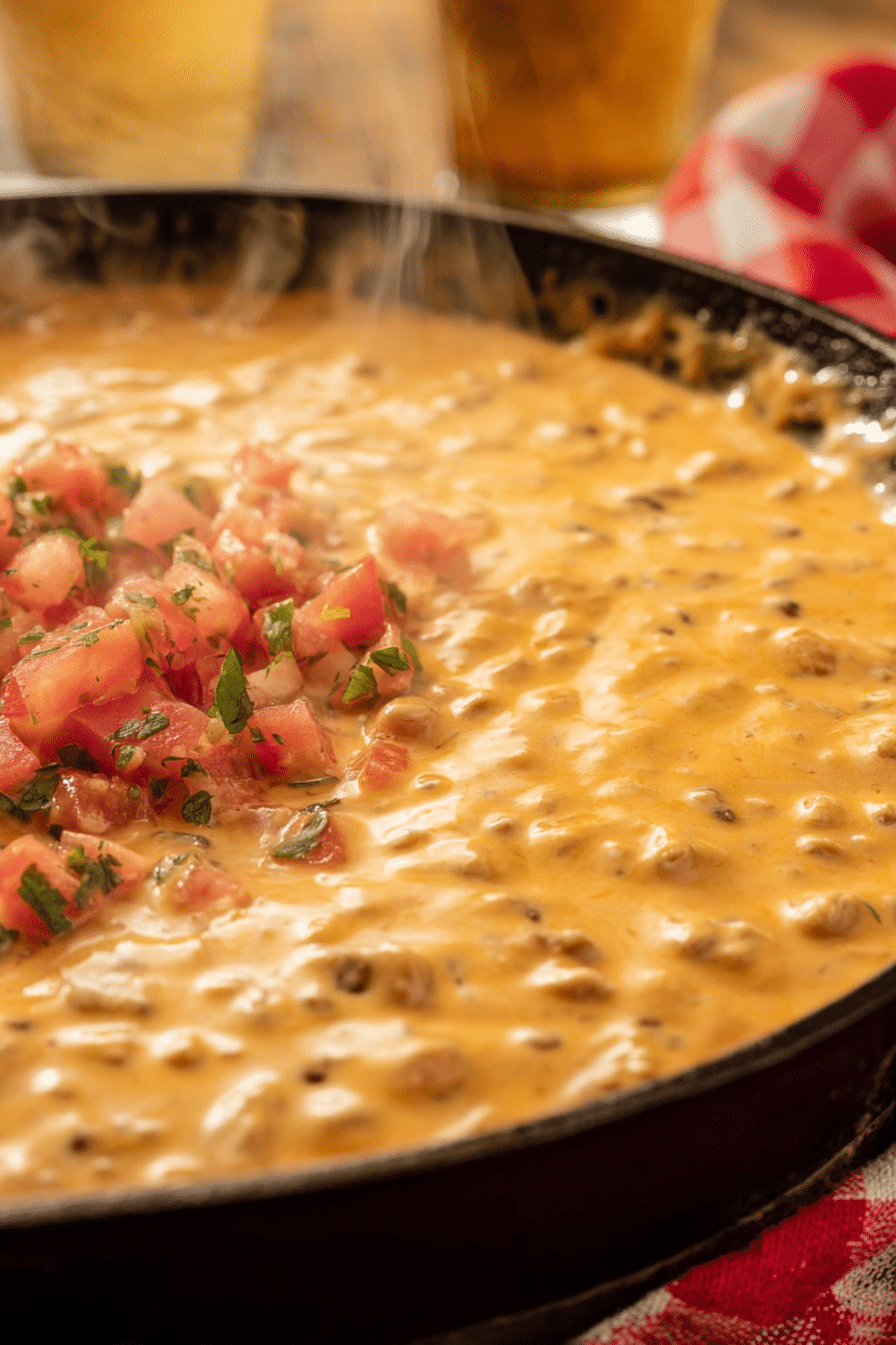 Delicious smoked queso in a cast iron skillet surrounded by tortilla chips and fresh cilantro, ideal for game day or summer barbecues.