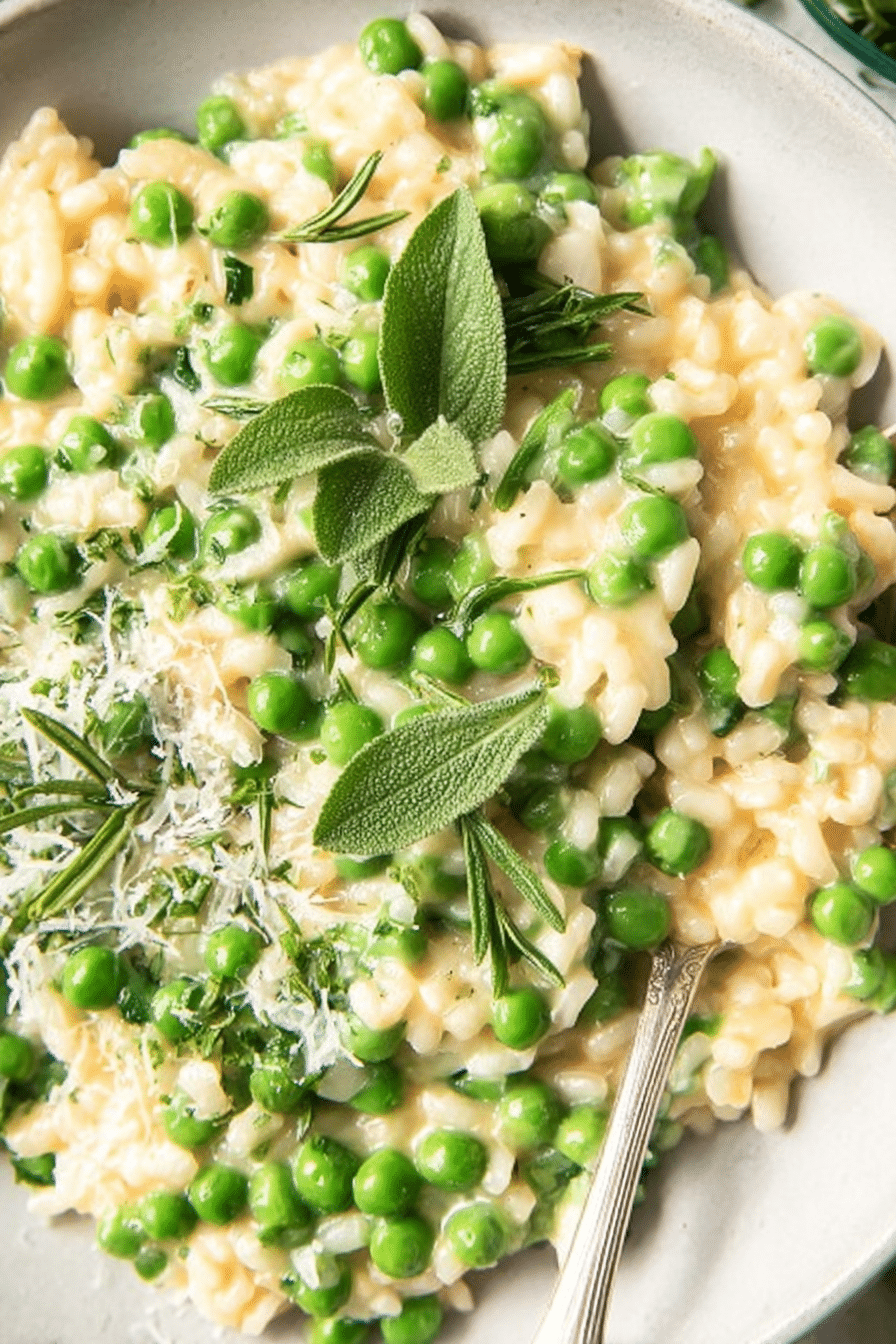 Close-up of creamy spring pea risotto with fresh herbs and green peas on top.