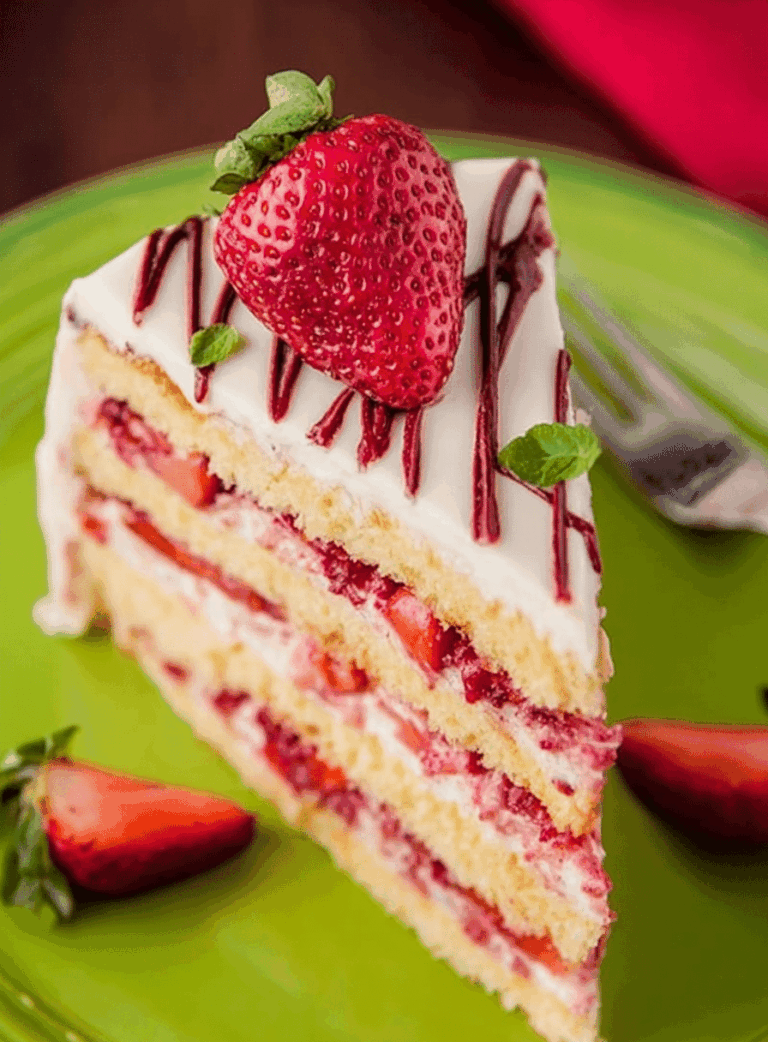 Deliciously sliced strawberry layer cake with fresh strawberries and cream cheese frosting on a wooden table