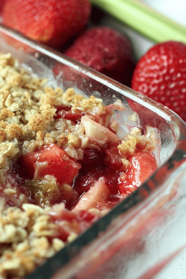 Warm strawberry rhubarb crisp topped with vanilla ice cream in a decorative bowl