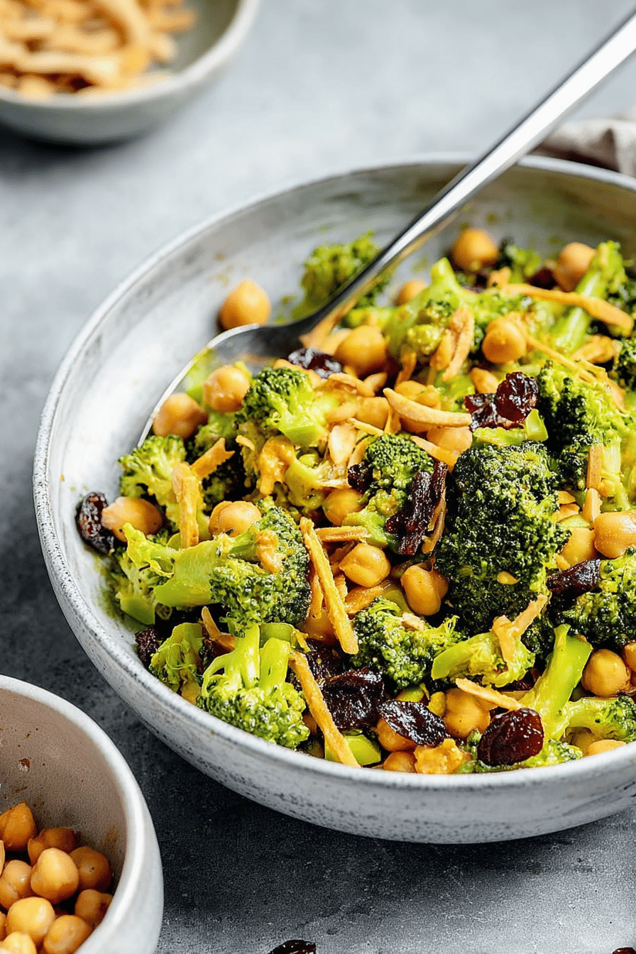Vegan curried broccoli chickpea salad served in a bowl with colorful ingredients and garnishes.
