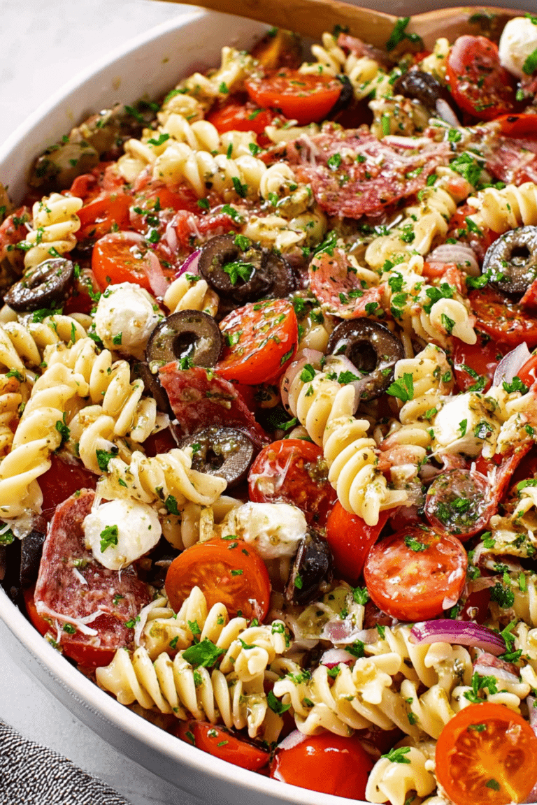 Colorful zesty Italian pasta salad with cherry tomatoes, bell peppers, and mozzarella pearls in a large serving bowl.