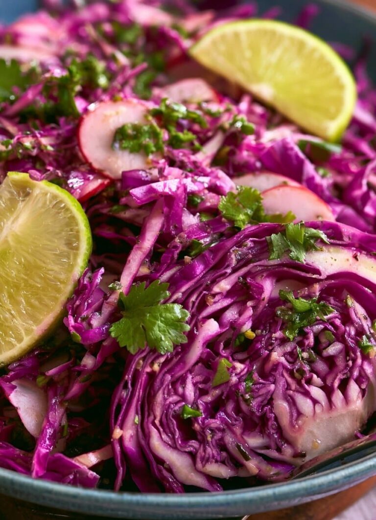A colorful cabbage-radish slaw with cilantro-lime vinaigrette served in a wooden bowl, showcasing green and savoy cabbage, watermelon radishes, and fresh cilantro.